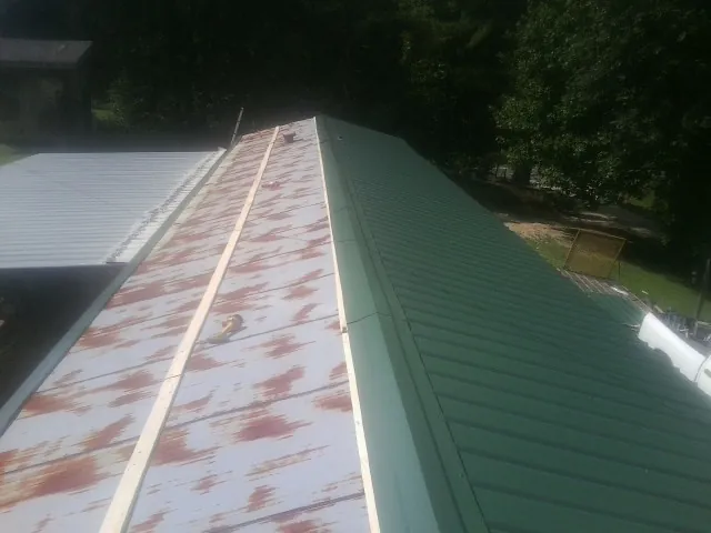Old rusted panels beside newly installed green metal roofing — Wind Damage Roof Repair by Roofing Brothers in Huntley