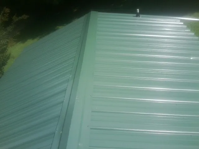 New green metal panels meeting at the ridge of a roof — Flat Roof Repair work by our crew in Huntley