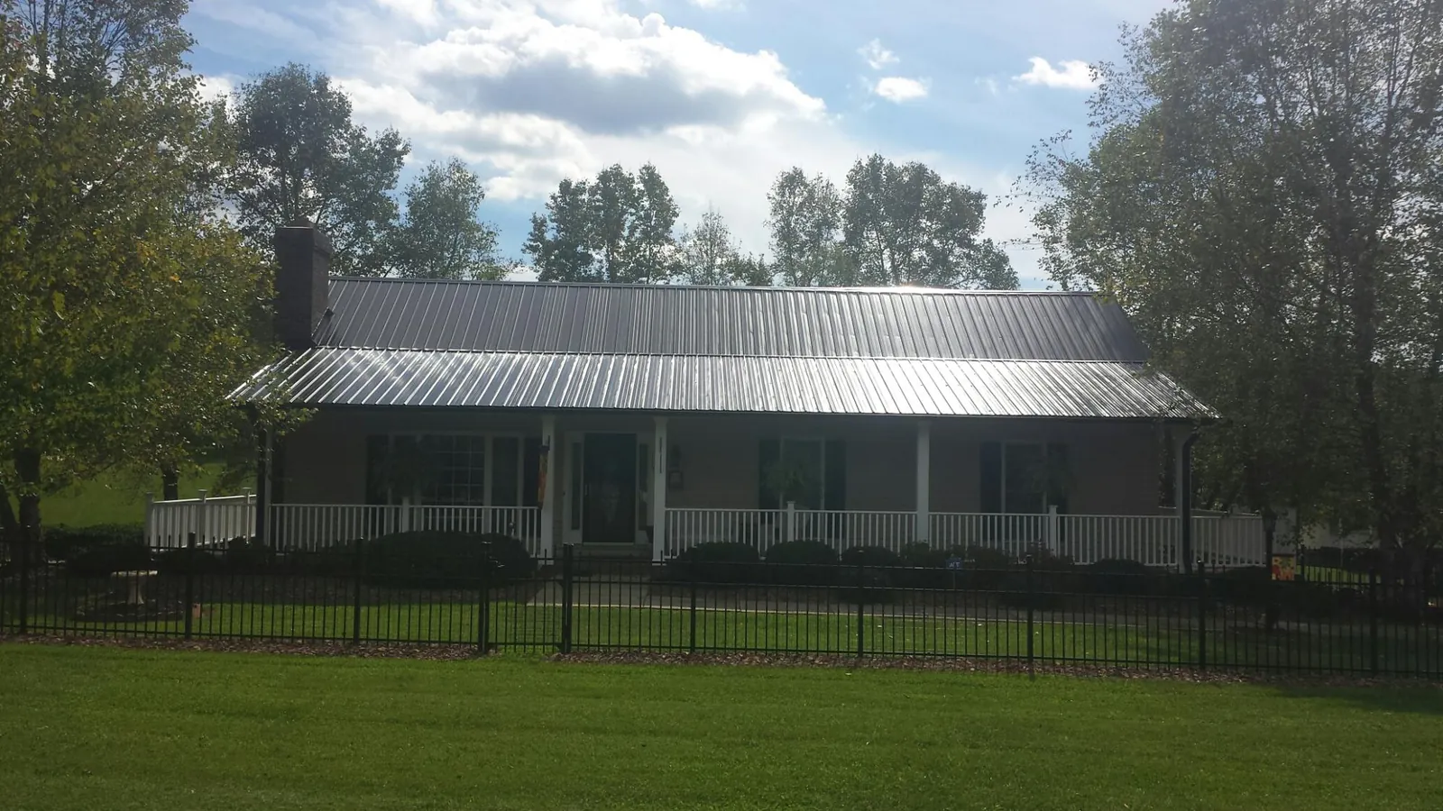 Gray metal roof on a brick ranch with a full width front porch — Gutter Guard Installation work by our crew in Huntley